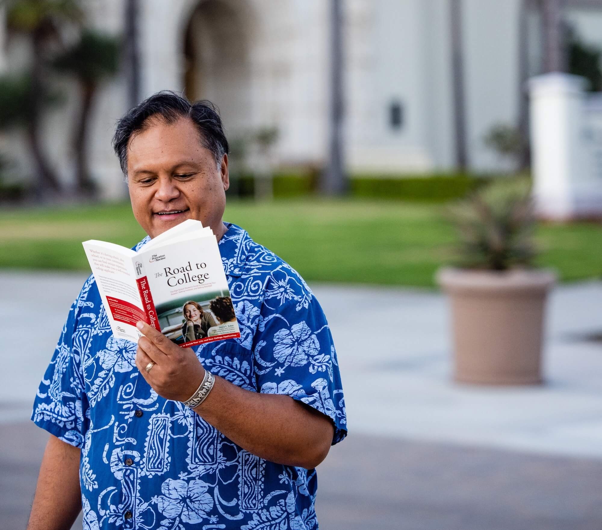 Mr. T holding Road to College book on university campus